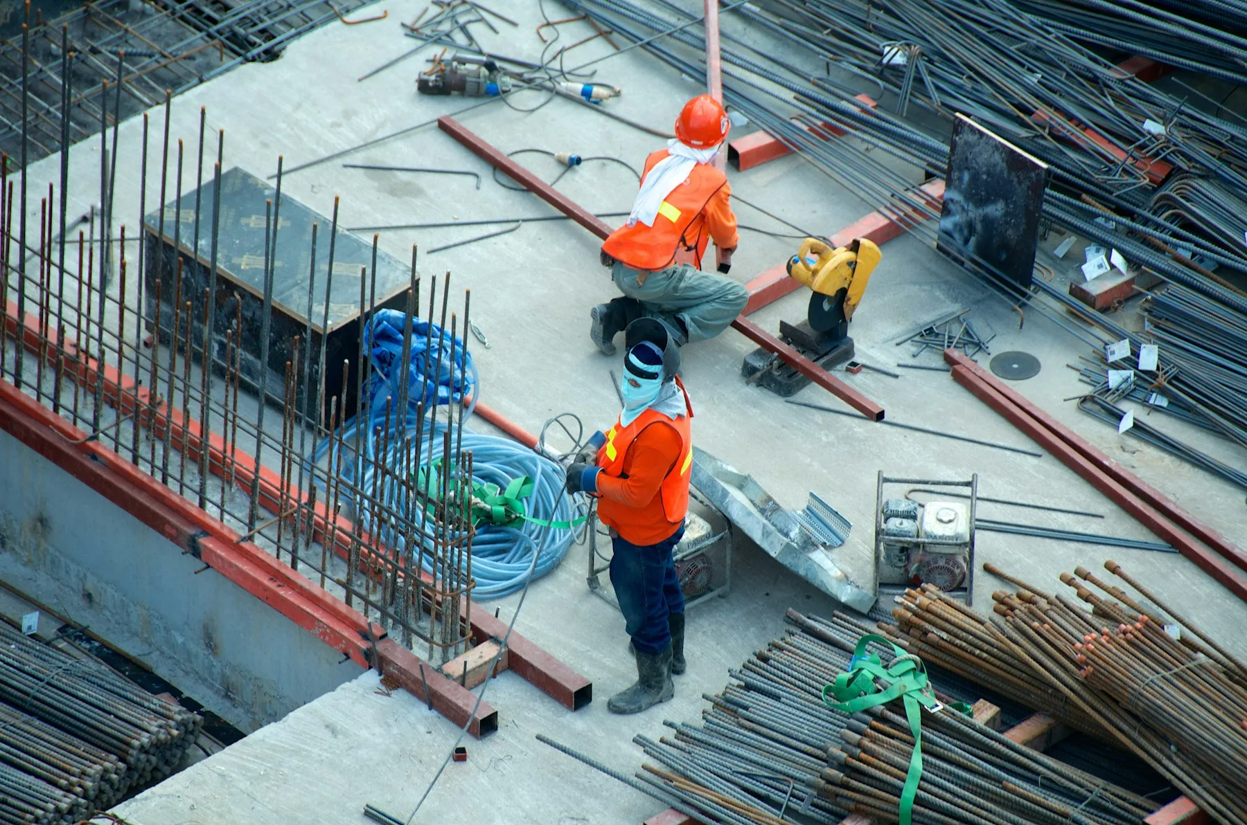 A residential construction site mid-build — cranes and framework against a clear sky.
