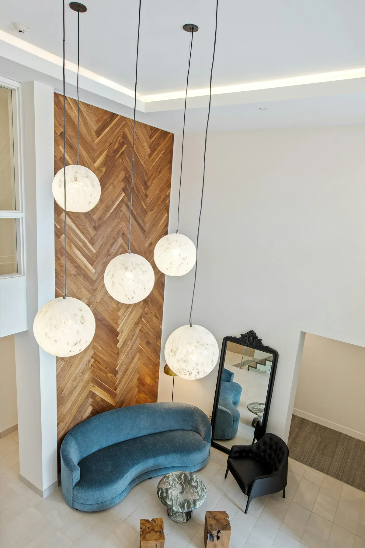 A warm residential lobby with wood details, seating, and pendant lights.