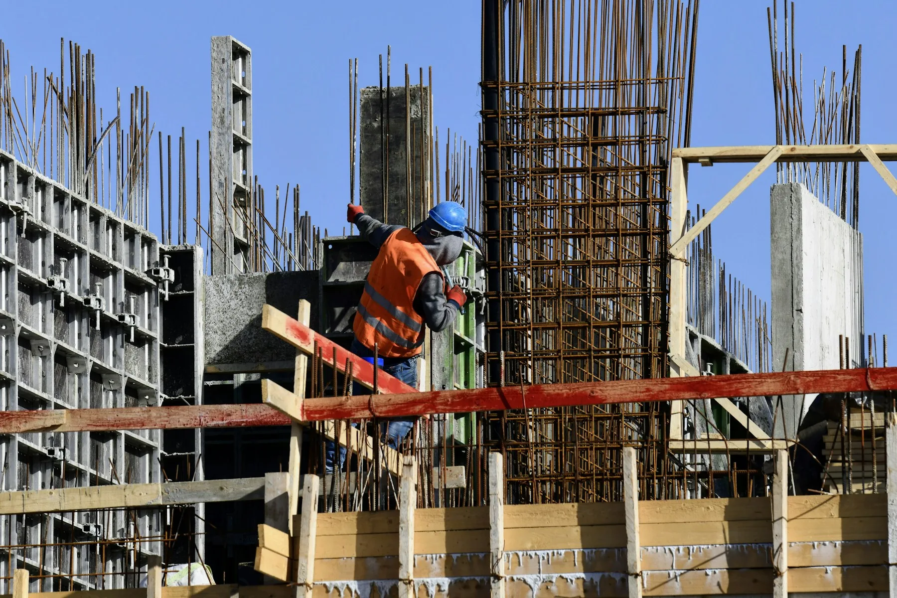 A construction worker on an active residential site, with concrete structure rising behind him.