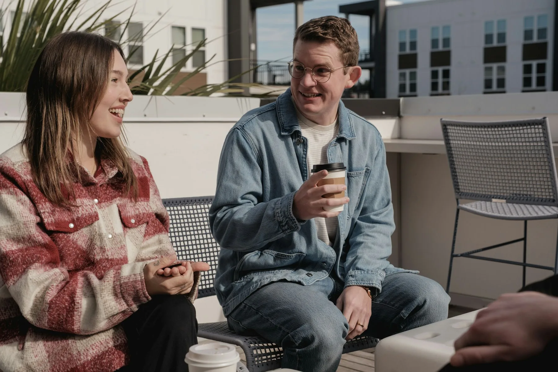 Two neighbours talking over coffee on an apartment rooftop.