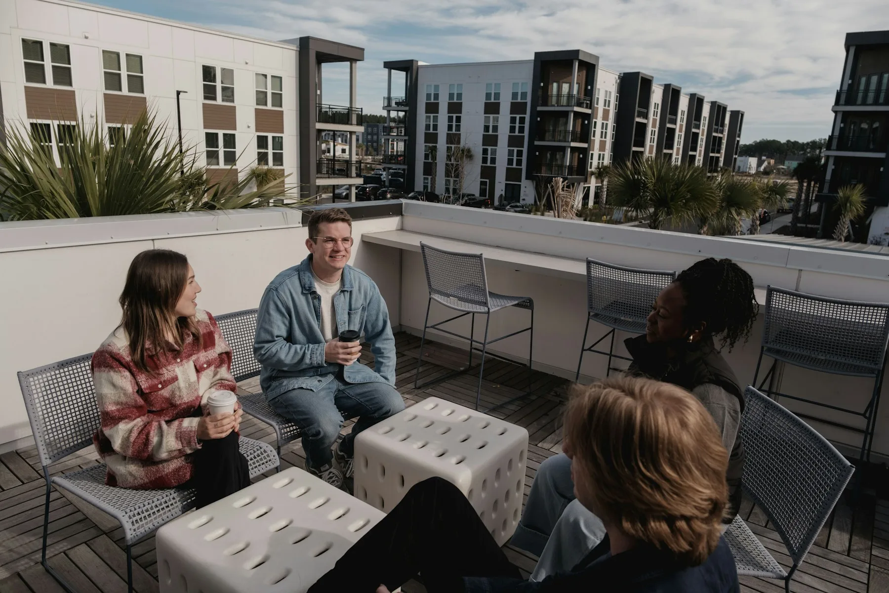 Future neighbours sitting together on a rooftop terrace beside a modern apartment building.